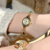 Gold vintage-style bracelet watch with green gem accents and textured knit sleeve
