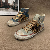 High-top denim sneakers with metallic gold laces, studded accents, and distressed detailing