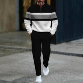 Man wearing a black and white colorblock pullover, black pants, white sneakers, modern fit.