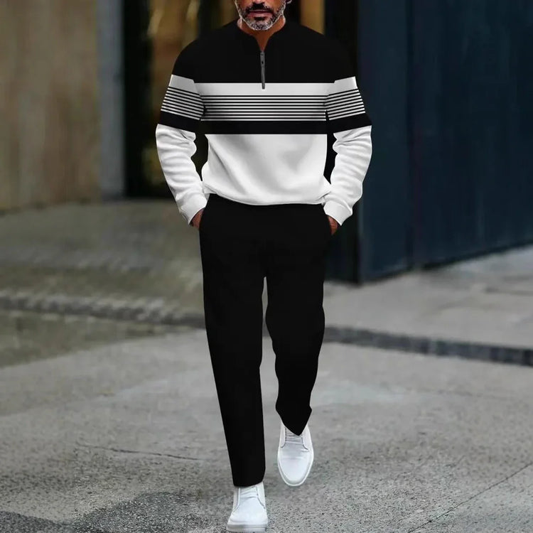 Man wearing a black and white colorblock pullover, black pants, white sneakers, modern fit.