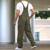 Man wearing olive green loose-fit denim overalls with white t-shirt and sneakers
