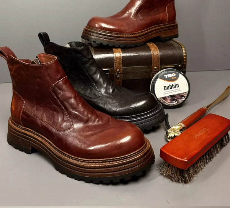 Chunky brown and black leather ankle boots with thick rubber soles, casual fit, next to shoe care items.