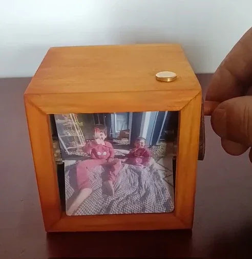 Hand-cranked wooden photo box displaying a printed image on a tabletop