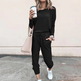 Woman wearing black casual jogger set with long sleeves, tapered pants, and white sneakers