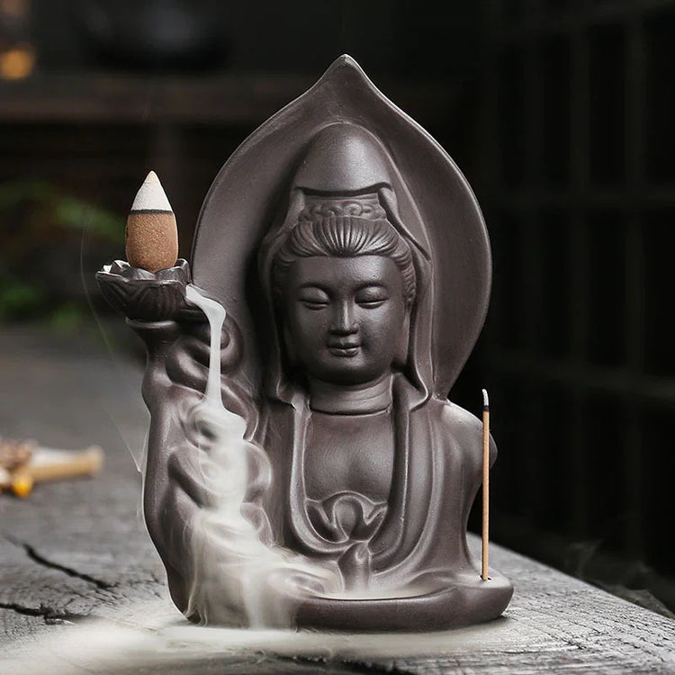 Matte ceramic statue incense burner with flowing smoke and detailed robe design, seen on wooden surface.