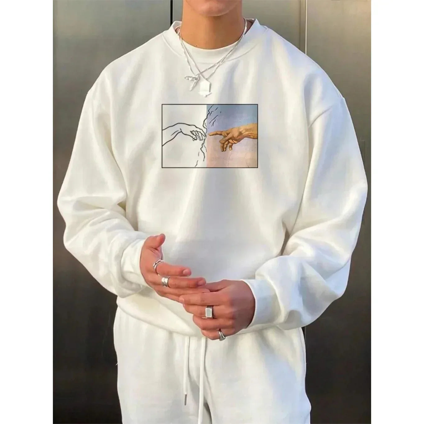 White oversized sweatshirt with artistic hand graphic, paired with matching joggers, cotton material.