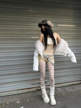 Woman in beige mesh romper, white faux fur jacket, striped tights, chunky boots, and a faux fur cap posing in streetwear style.