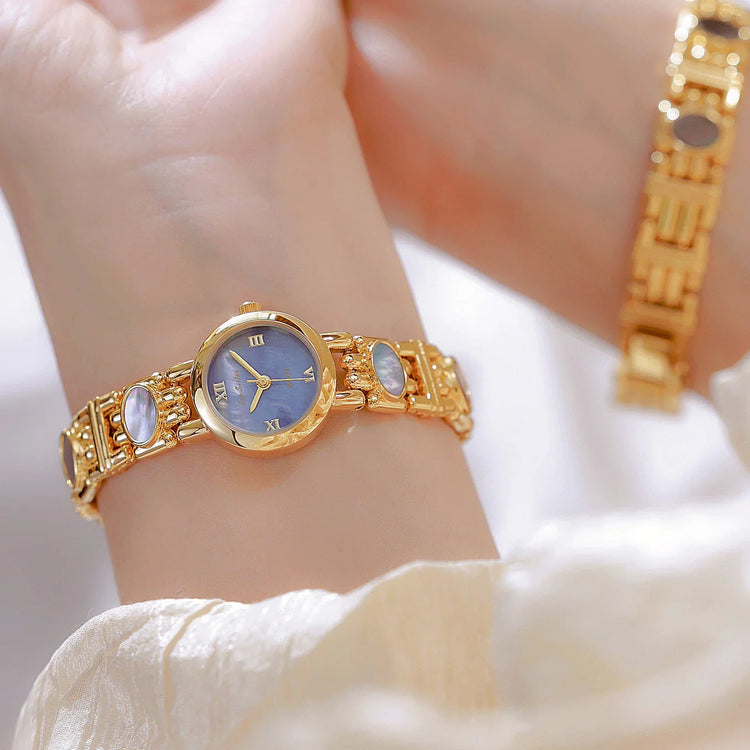 Gold bracelet watch with blue face and mother of pearl accents, elegant wrist fit.