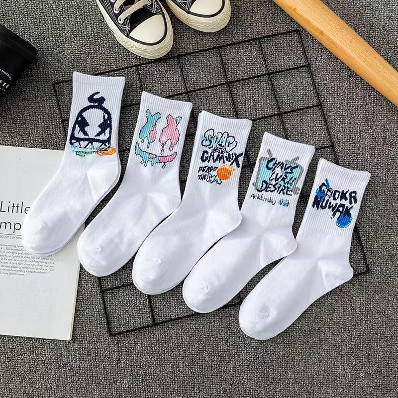 Five pairs of white cotton crew socks with colorful graffiti streetwear designs, laid on a gray surface.