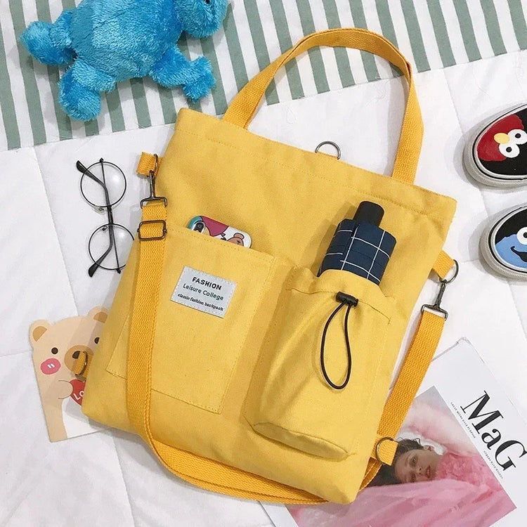 Yellow canvas shoulder bag with front pockets, casual streetwear style, relaxed fit.