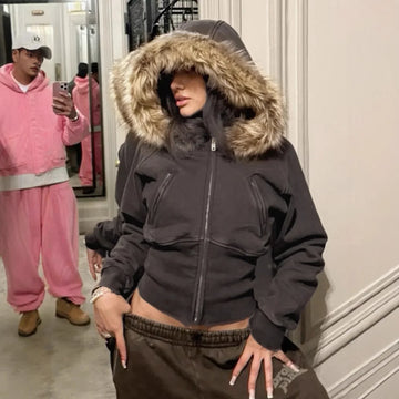 Woman in a fitted black hoodie with faux fur trim and brown sweatpants, streetwear style.
