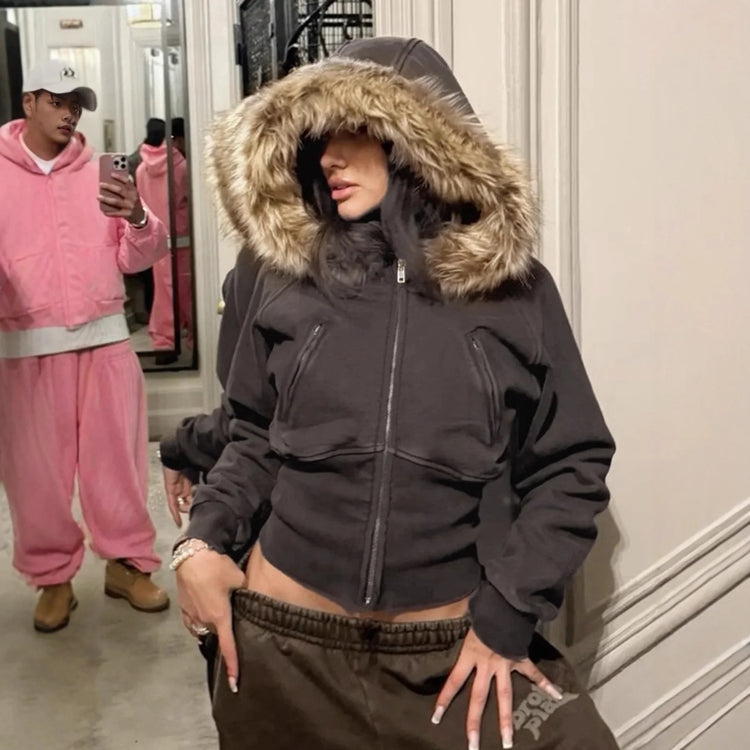 Woman in a fitted black hoodie with faux fur trim and brown sweatpants, streetwear style.
