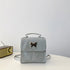 Glossy silver mini backpack with butterfly metal accent, structured design, adjustable straps