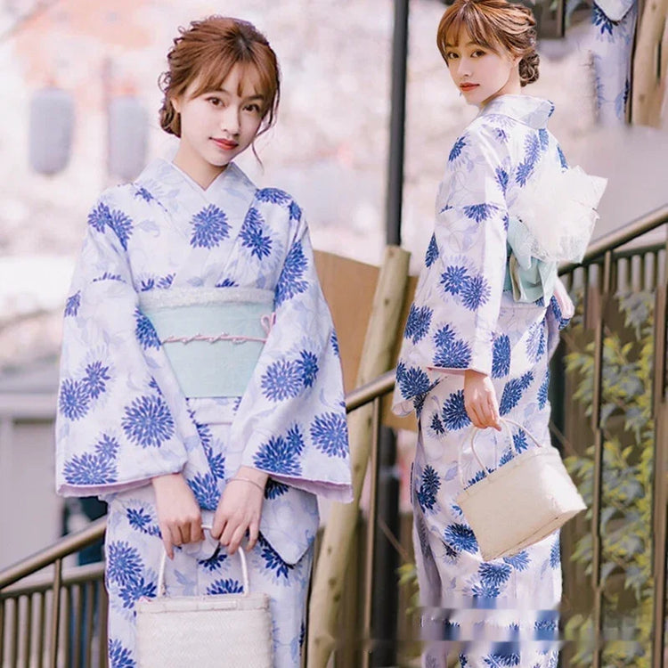 Woman wearing a blue floral kimono with light blue sash, loose fit, holding a woven handbag