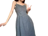 Woman wearing a sleeveless denim dress with spaghetti straps and relaxed fit