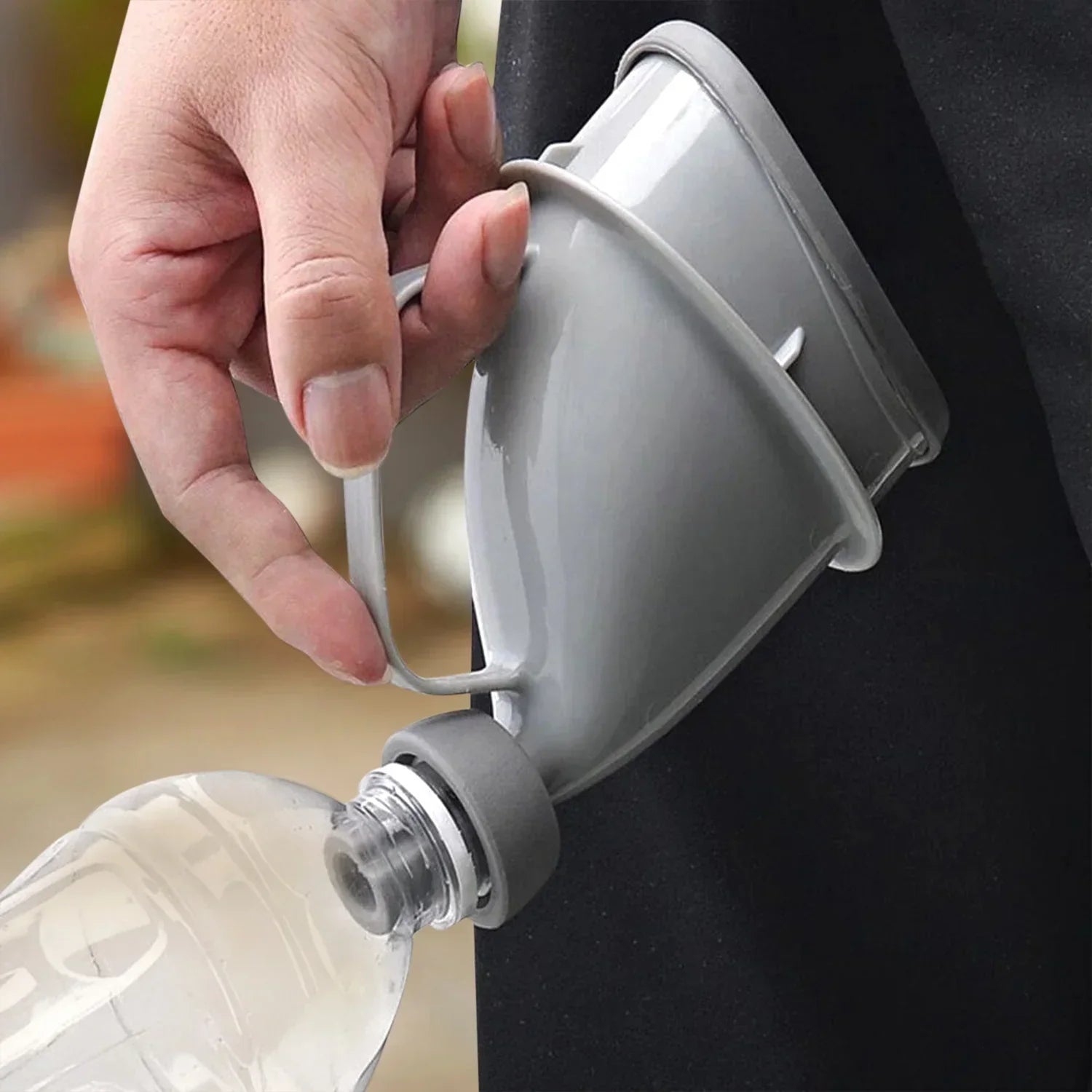 Hand holding a gray plastic portable funnel attached to a clear water bottle
