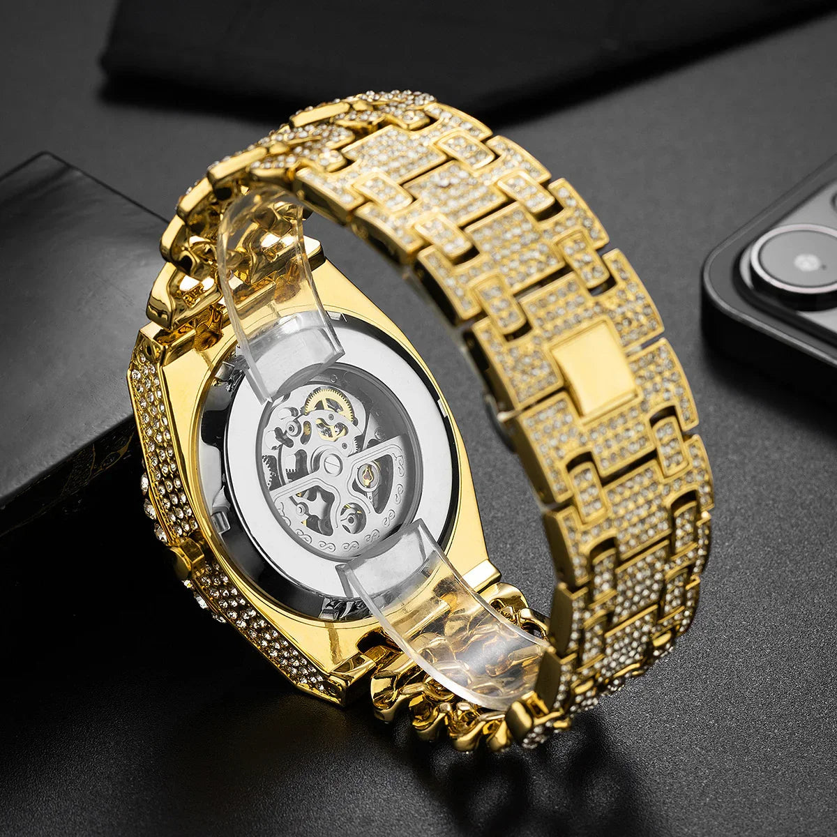 Close-up of a gold-tone watch with crystal-studded metal band and visible mechanical movement