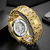 Close-up of a gold-tone watch with crystal-studded metal band and visible mechanical movement