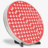 Round panel of red LED lights with silver rim on a black stand, tech accessory.