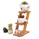 Modern wooden plant stand with white ceramic pots holding succulents and small figurines