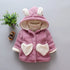 Pink sherpa fleece toddler jacket with heart pockets and bunny ear hood, cozy loose fit.