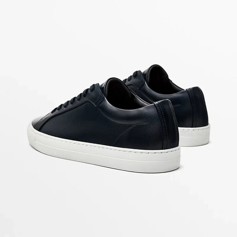 Black leather low-top sneakers with white rubber soles and minimalist design