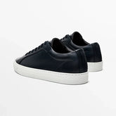Black leather low-top sneakers with white rubber soles and minimalist design