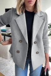 Woman wearing a light gray double-breasted blazer with ribbed knit sleeves, casual fit, paired with jeans.