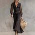 Woman wearing a black sheer sleeve button-down maxi dress with a fitted waist and flared skirt