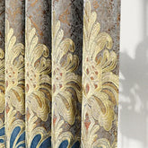 Closeup of ornate embroidered curtain with gold floral patterns and metallic gray fabric.