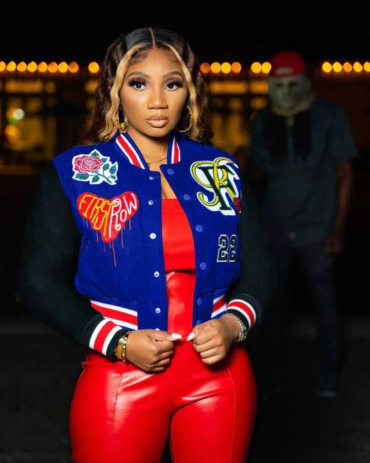 Woman in blue and black varsity jacket with patches, red faux leather pants and top, streetwear style