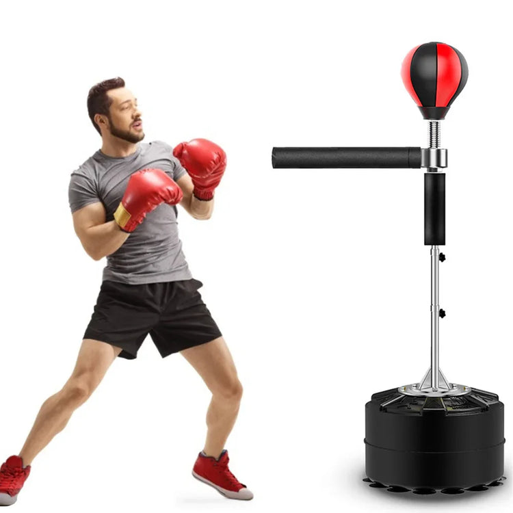 Man in gray athletic T-shirt and black shorts boxing with red gloves next to a standing punching ball.
