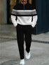 Man wearing black and white striped pullover, black pants, white sneakers, modern streetwear style