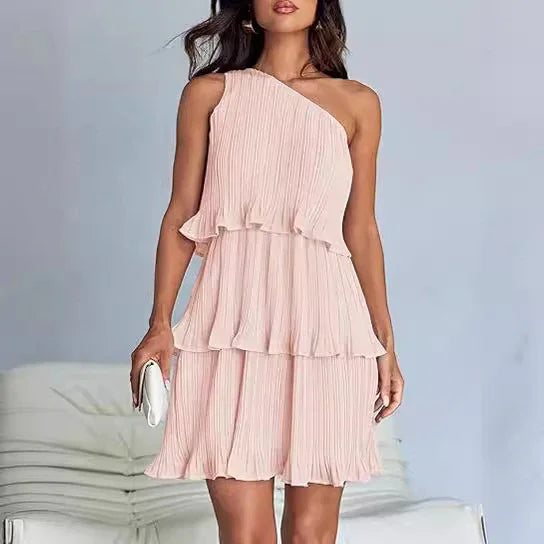 Woman wearing a light pink one-shoulder pleated chiffon dress with tiered ruffles