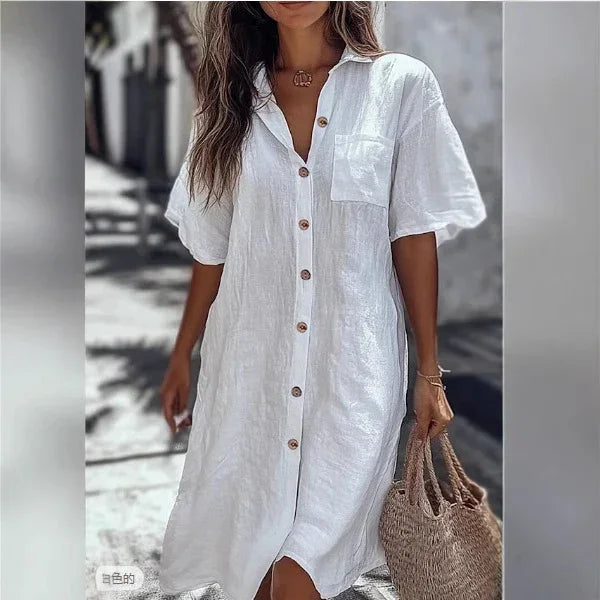 Woman wearing loose white linen button-up shirt dress with short sleeves, front pocket, and relaxed fit