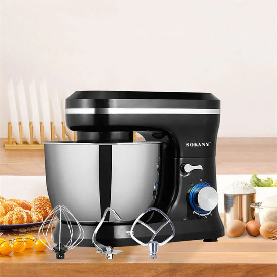 Black and silver stand mixer with stainless steel bowl and three metal attachments on a kitchen counter