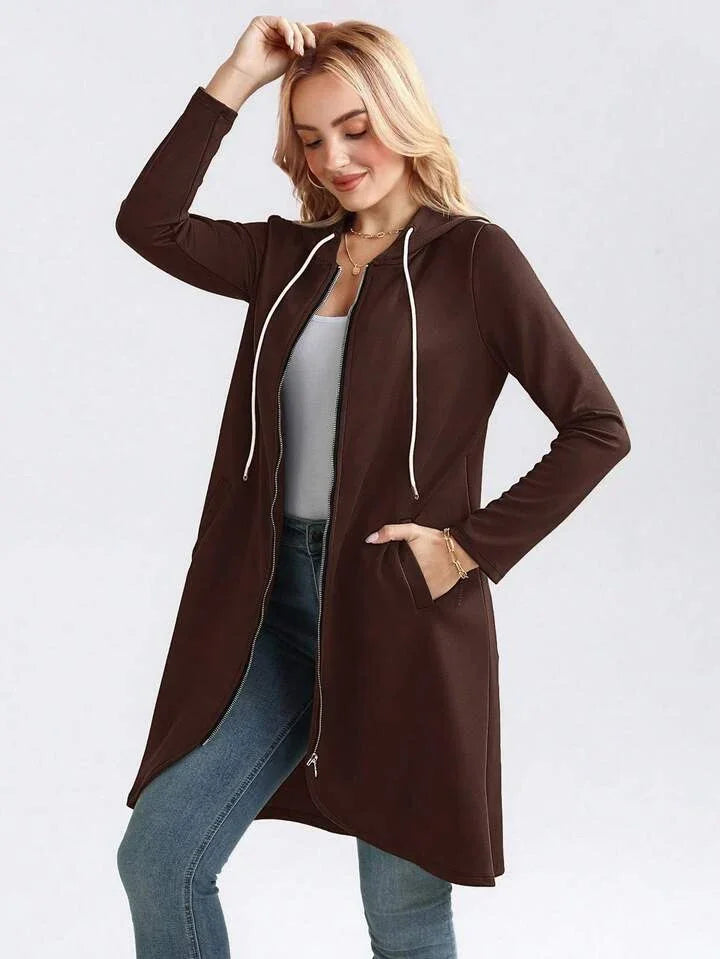 Woman wearing a long brown zip-up hoodie jacket with pockets, casual fit, paired with jeans.