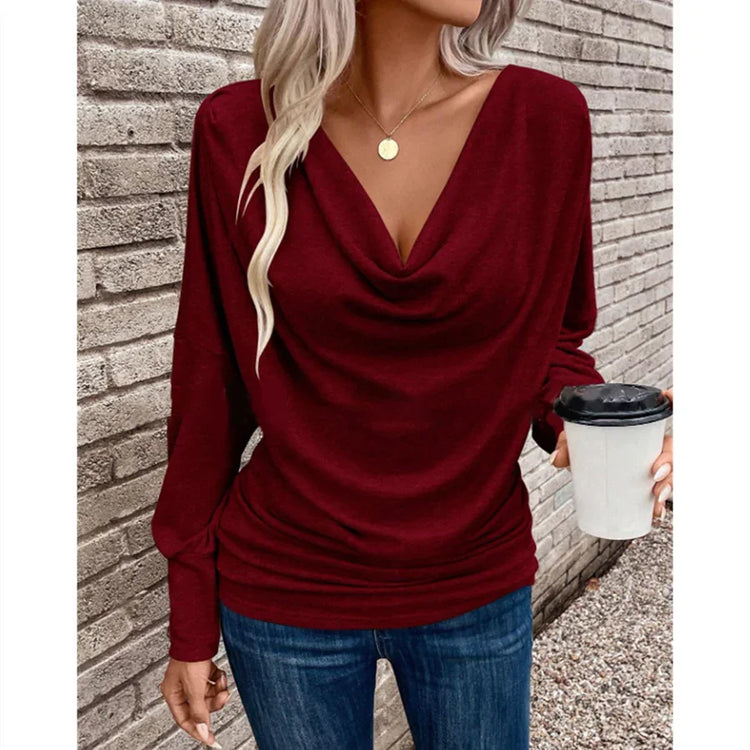 Woman wearing a burgundy cowl neck long sleeve top with relaxed fit and blue jeans