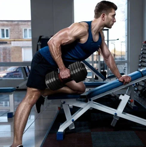 Man in navy sleeveless athletic tank top and black shorts lifting dumbbell at gym