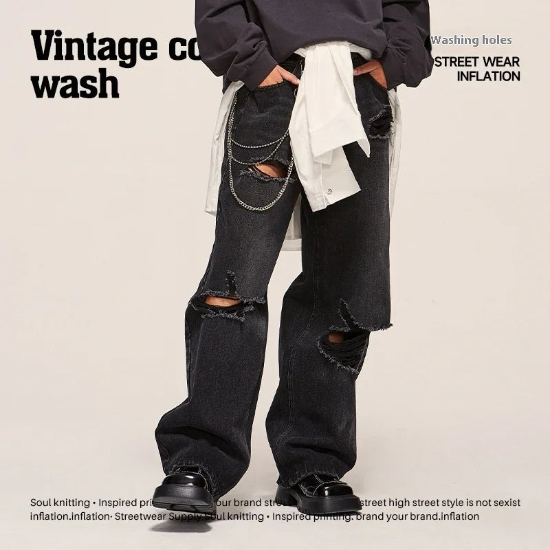Black distressed straight-leg jeans with ripped knees, loose fit, chain detail, streetwear style.