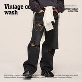 Black distressed straight-leg jeans with ripped knees, loose fit, chain detail, streetwear style.