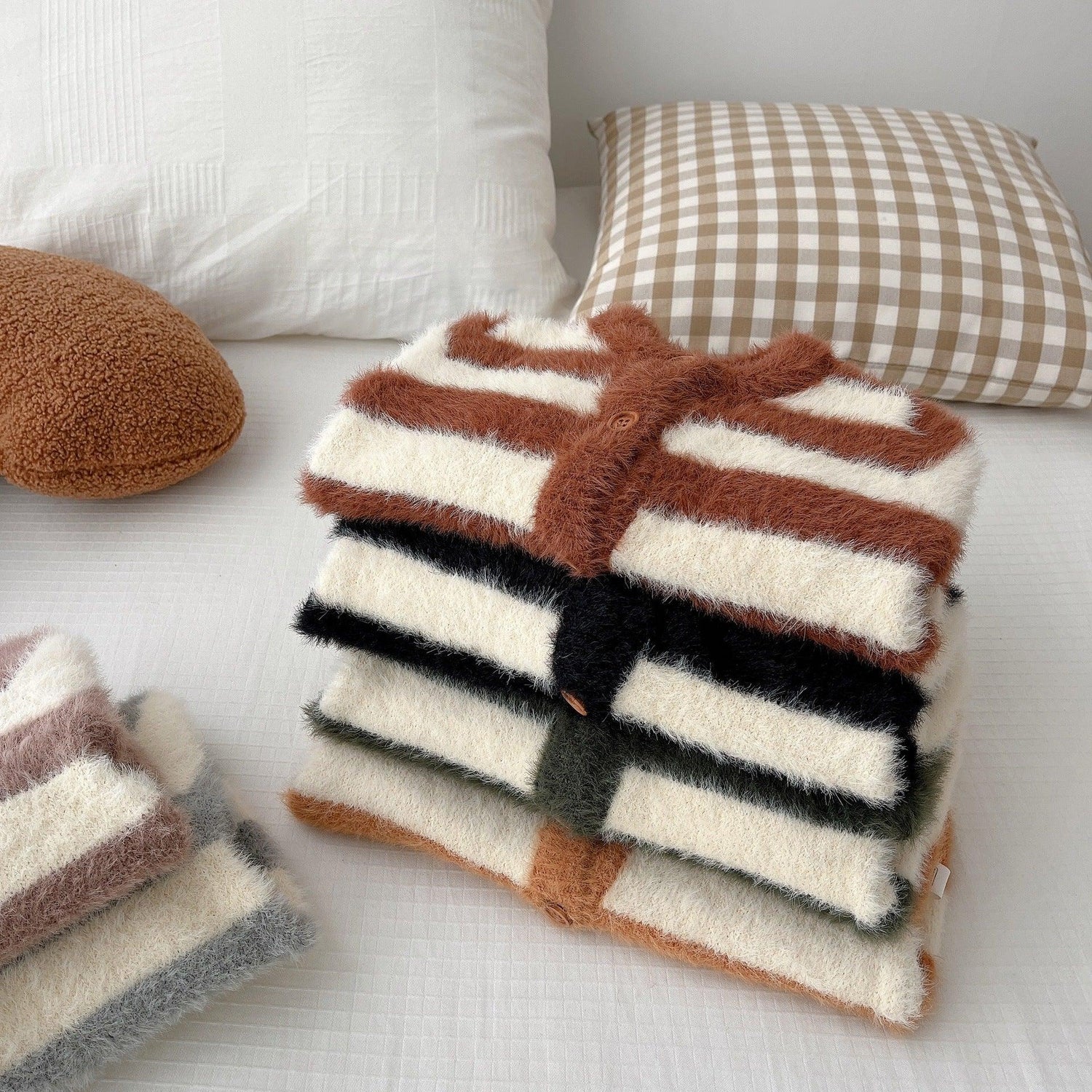 Stack of fuzzy striped cardigans in brown, black, and green tones, soft knit, relaxed fit