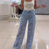 Woman wearing light blue lace floral wide-leg jeans and a fitted white tank top.