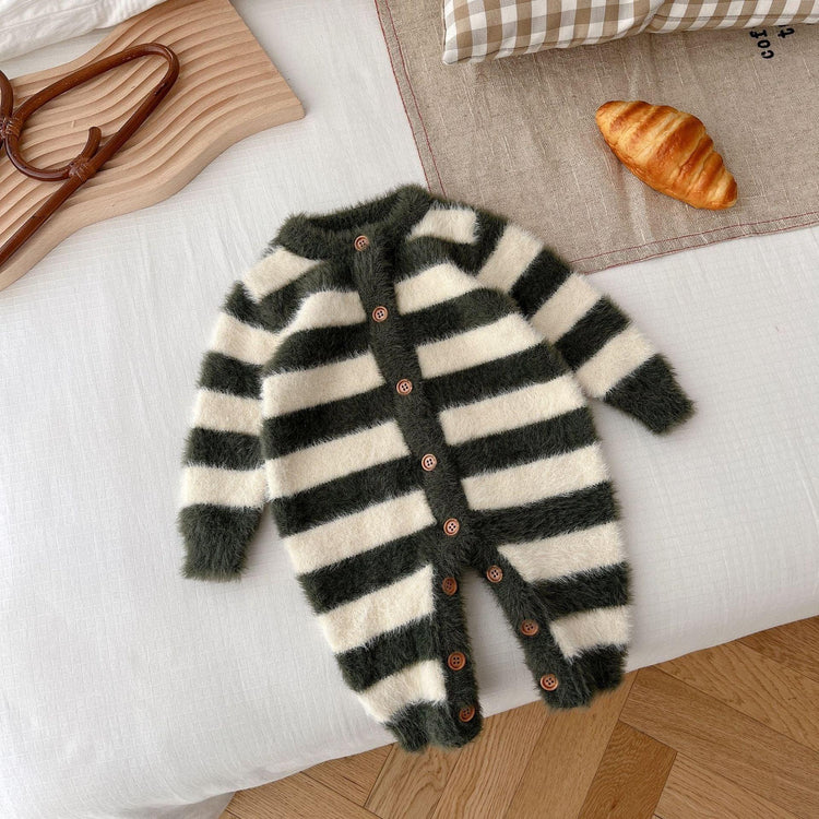 Fuzzy black and white striped baby jumpsuit with wooden buttons, laid flat on a bed