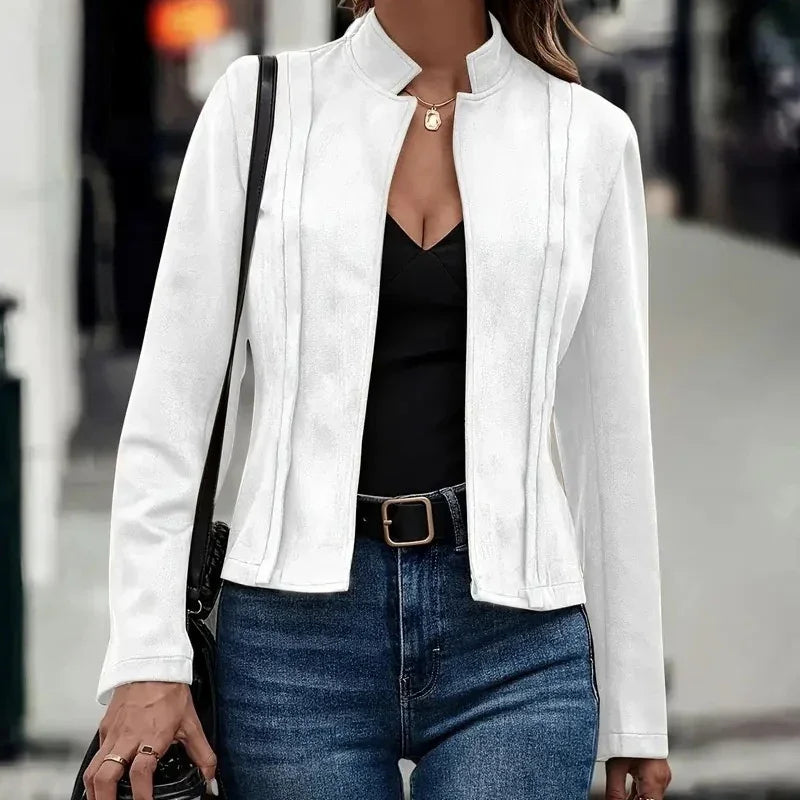 Woman wearing a fitted white suede jacket over a black top and blue jeans, casual street style