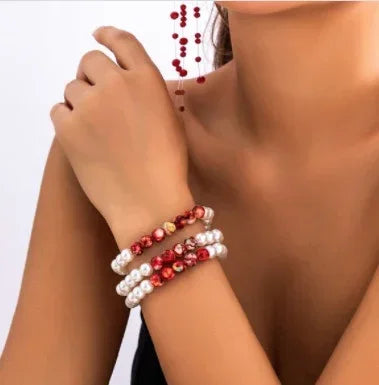 Woman wearing layered pearl and red beaded bracelets, elegant jewelry fashion accessory