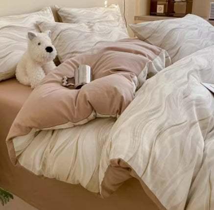 Beige and cream wavy-pattern bedding with soft, plush texture and relaxed fit, plush dog toy and metal mug on comforter