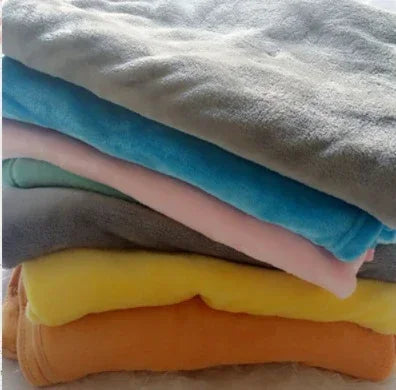 Stack of soft fleece blankets in gray, blue, pink, yellow, and orange, cozy and lightweight