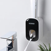 Wall-mounted automatic toothpaste dispenser in black and white plastic, modern bathroom setting
