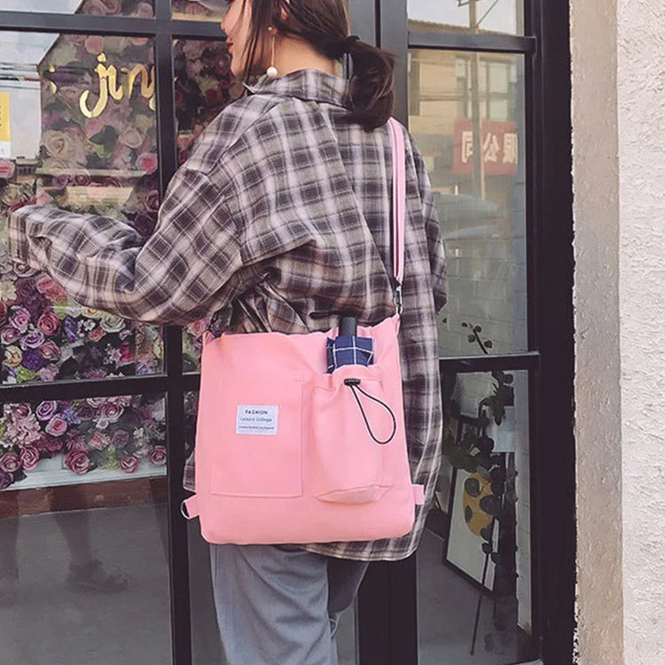 Woman wearing oversized plaid shirt and loose pants, carrying a light pink canvas shoulder bag